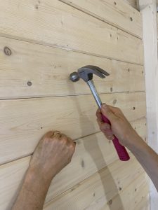 hammering nails into wall to hang picture